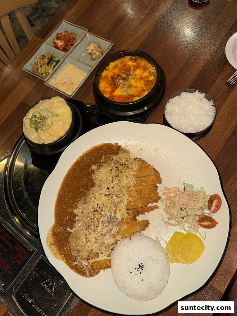 A delicious Korean meal featuring crispy pork cutlet, rice, and various side dishes.