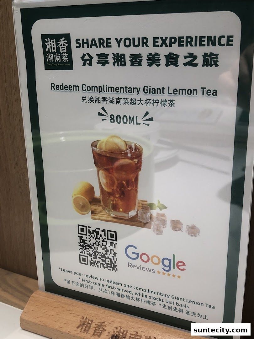 A sign offering a complimentary giant lemon tea for sharing an experience.