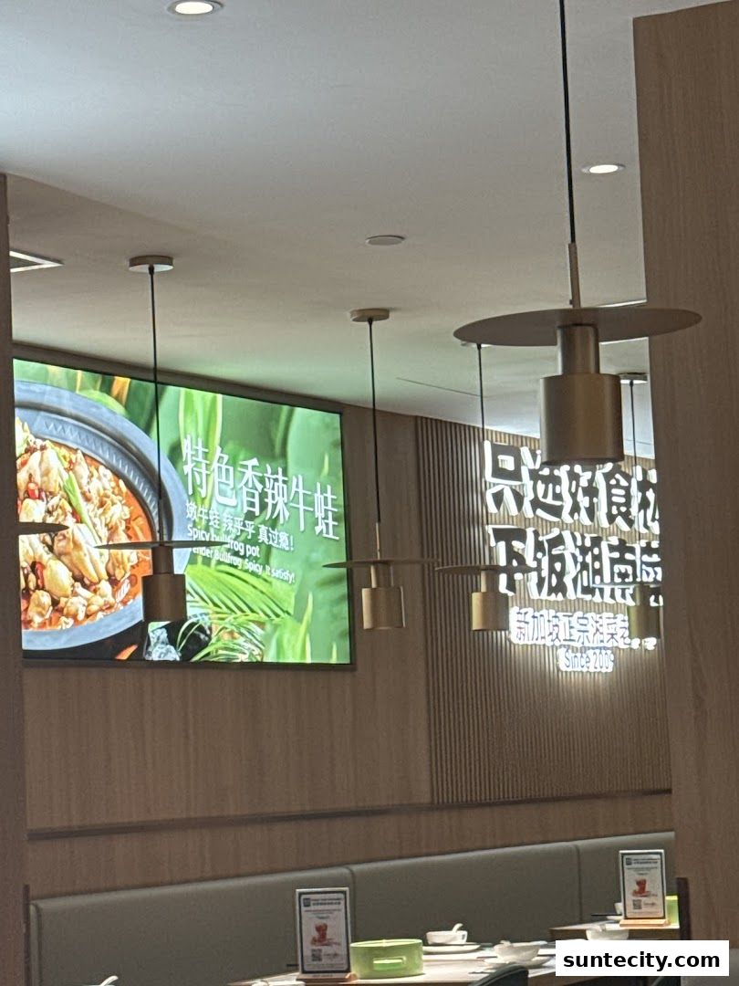 Interior of a restaurant with a large screen displaying food and neon signs.