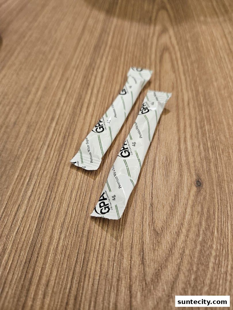 Two individually wrapped sugar packets with the brand GPA on a wooden surface.