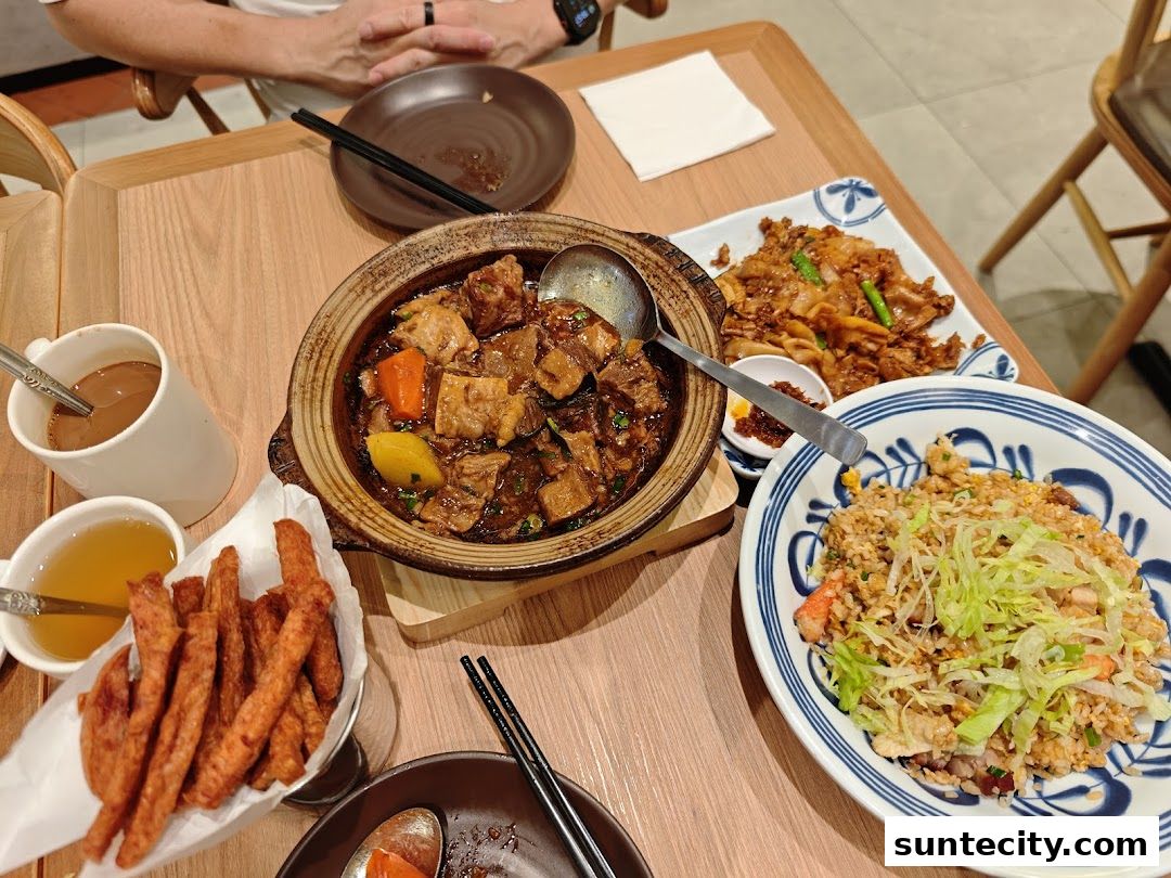 A table laden with Hong Kong-style dishes, including braised beef, fried noodles, and fried rice.