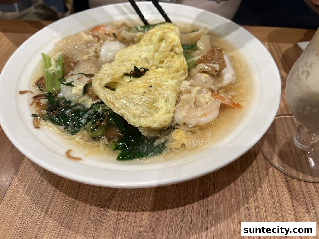 A close-up of a Hong Kong-style noodle dish with egg, shrimp, and vegetables.