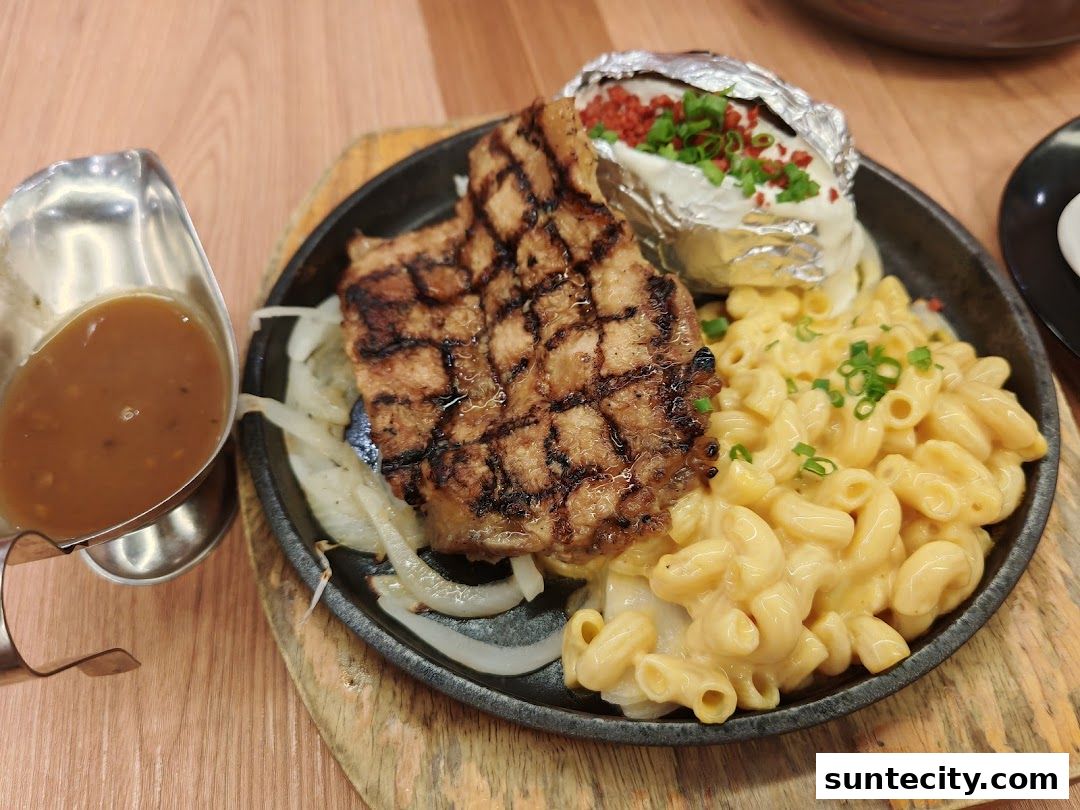 A sizzling steak with mac and cheese and a loaded baked potato served on a cast iron skillet.