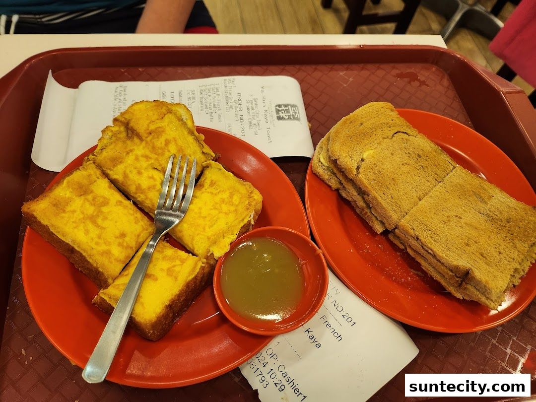 A tray with two plates of toast, one with French toast and kaya, the other with butter kaya toast.