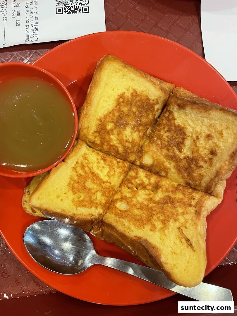 A close-up shot of kaya toast and a cup of drink on a red plate with a spoon.
