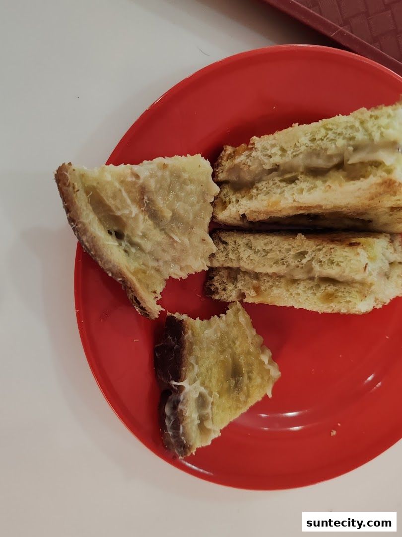 A close-up of kaya toast on a red plate, with some pieces already bitten.