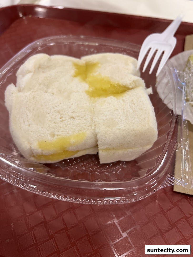 A close-up of Ya Kun Kaya Toast's signature kaya toast with butter, served in a clear plastic container.
