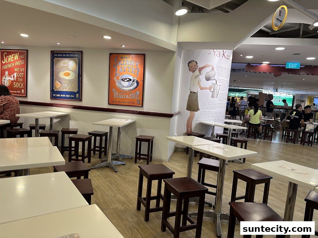 Interior of Ya Kun Kaya Toast with tables, stools, and vintage-style posters on the wall.