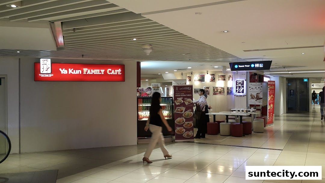 The Ya Kun Family Cafe storefront with a red illuminated sign and seating area.