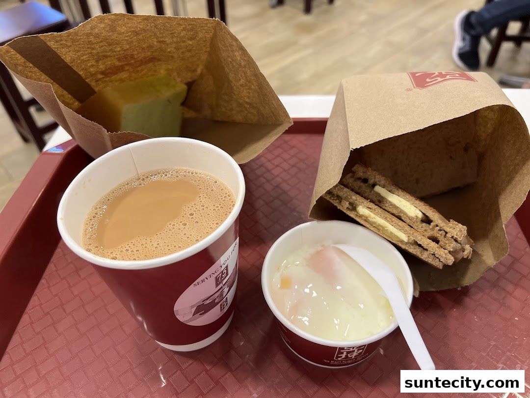 A tray with a cup of tea, kaya toast, soft-boiled eggs, and a slice of kaya bread.