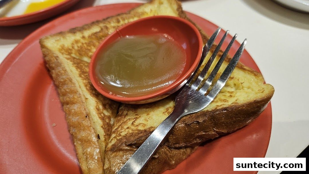 A close-up shot of French toast with kaya dip and a fork on a red plate.