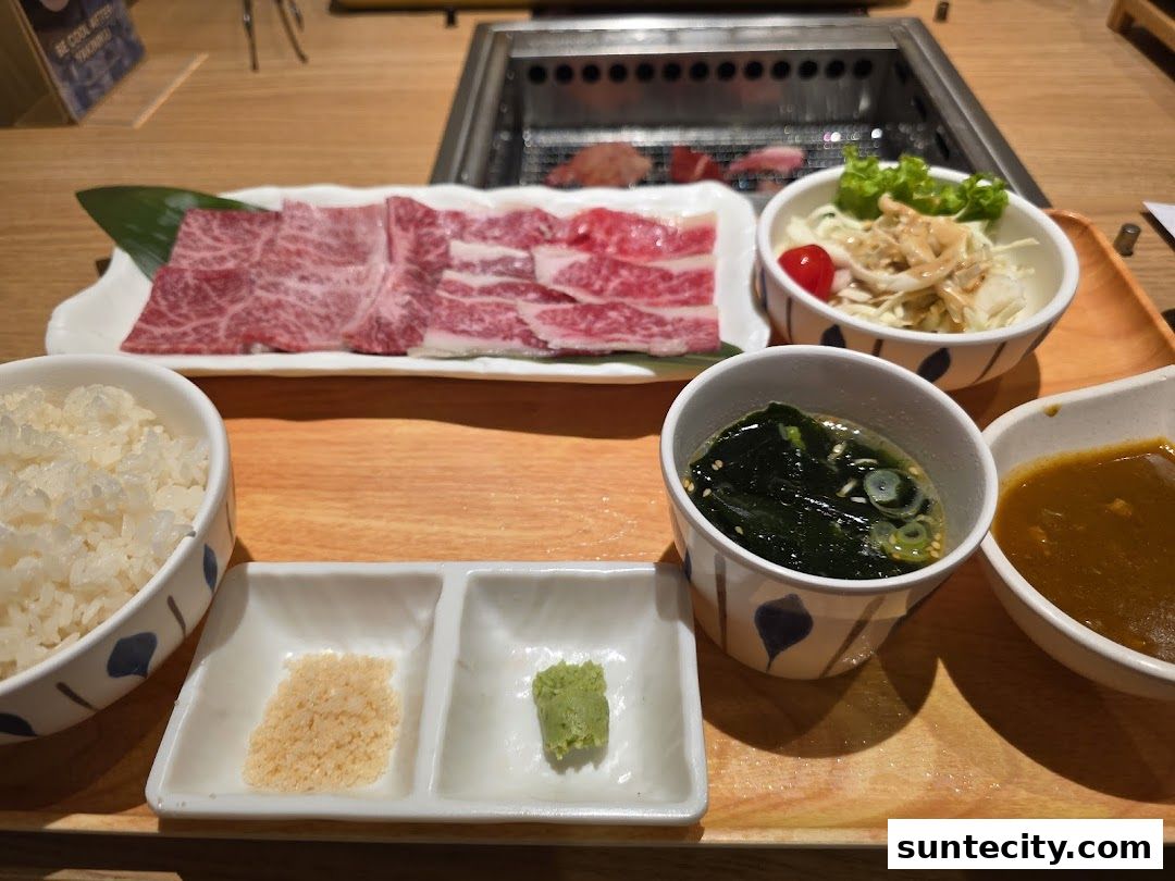 A delicious spread of thinly sliced raw beef, rice, soup, salad, and dipping sauces.