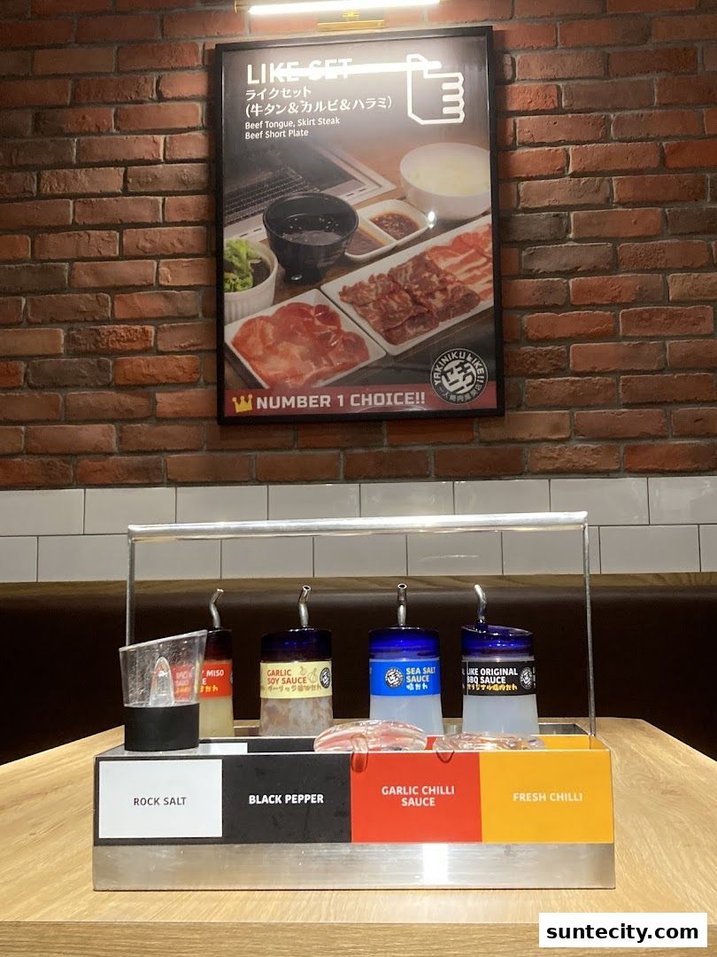 A display of sauces and seasonings at Yakiniku Like Suntec City, with a menu poster above.