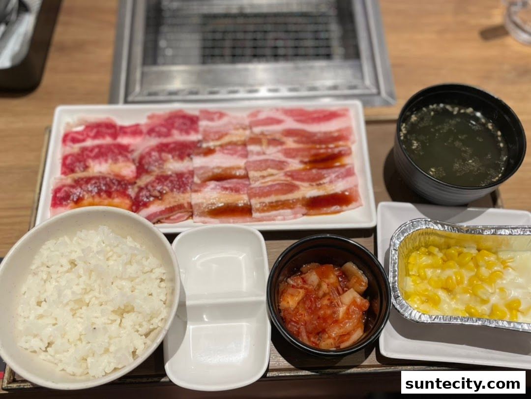 A delicious Yakiniku meal featuring thinly sliced meats, rice, soup, kimchi, and corn cheese.