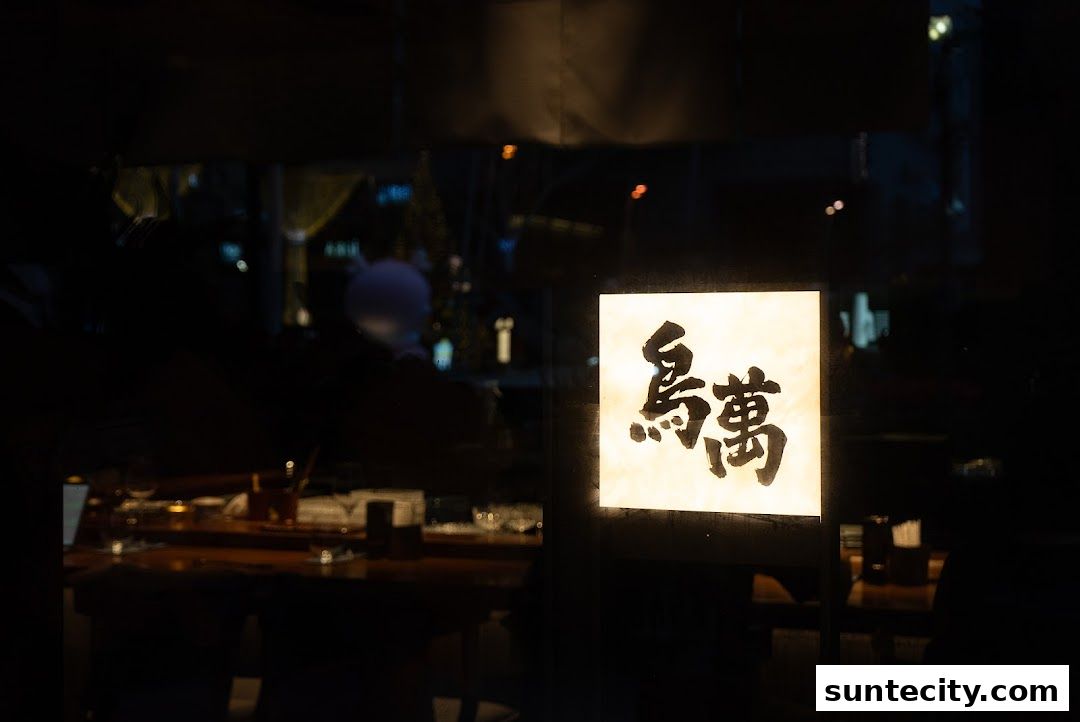 A glowing Japanese sign with calligraphy is visible through a dark window, hinting at a restaurant interior.