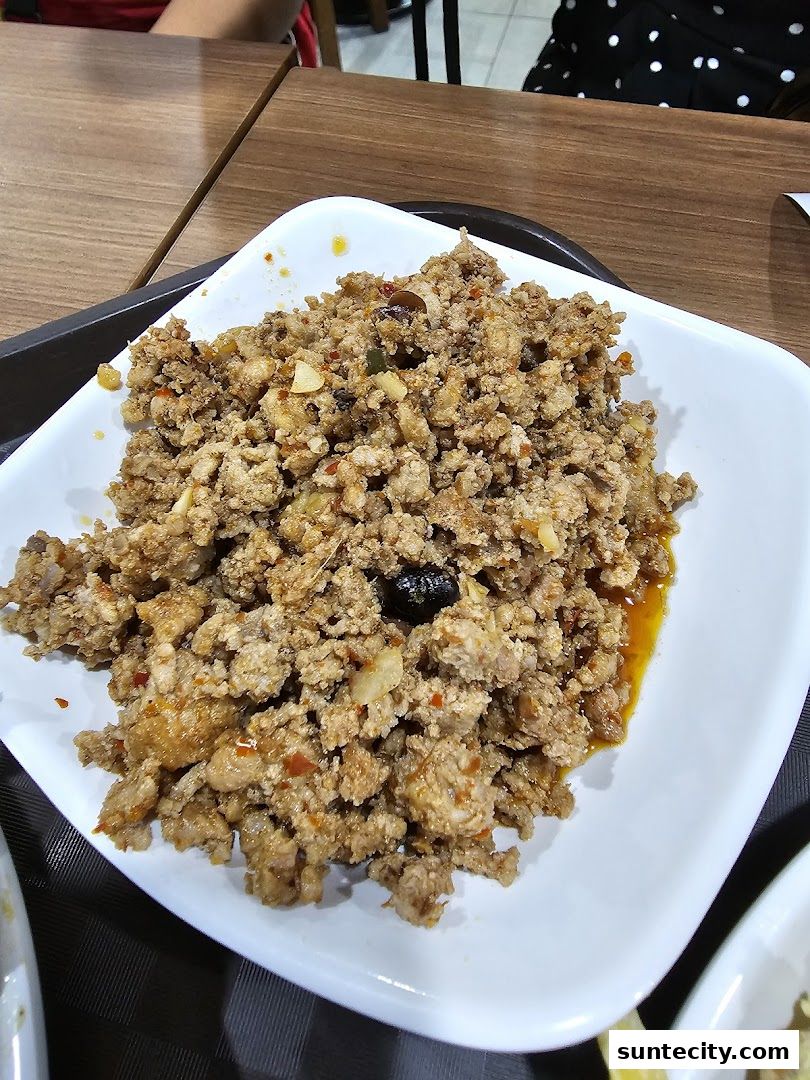 A close-up shot of a plate of minced meat dish with visible chili and garlic.