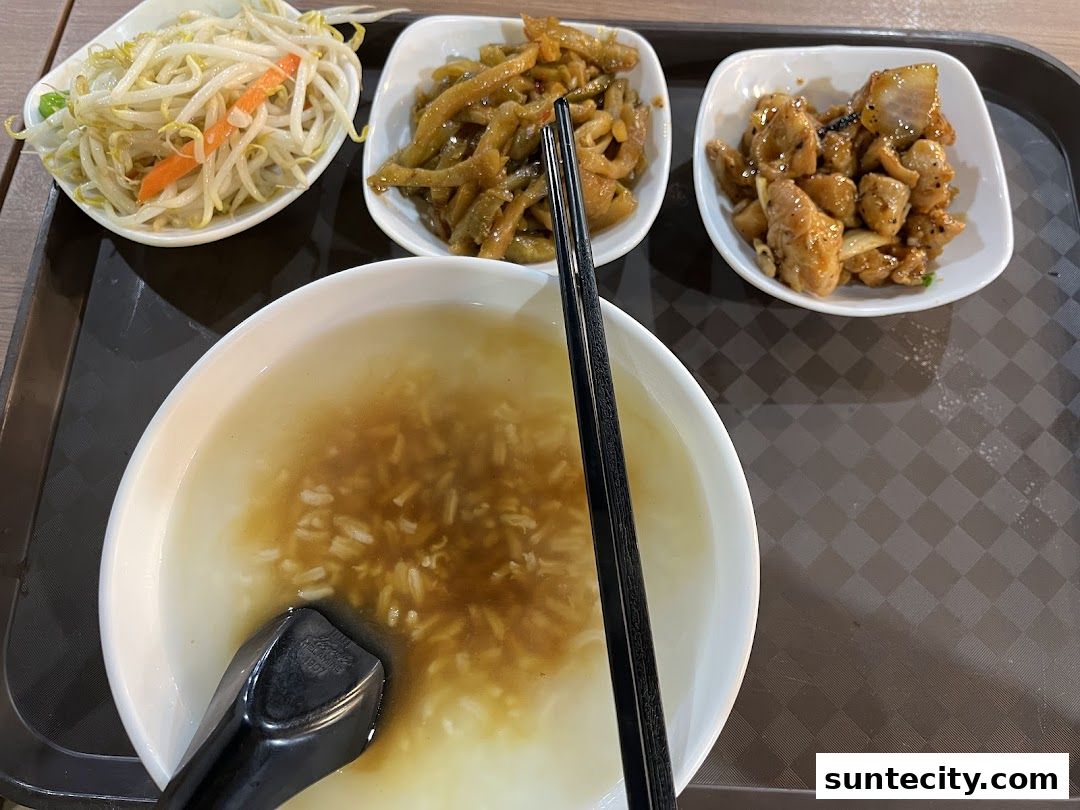 A bowl of Teochew porridge with three side dishes on a tray.
