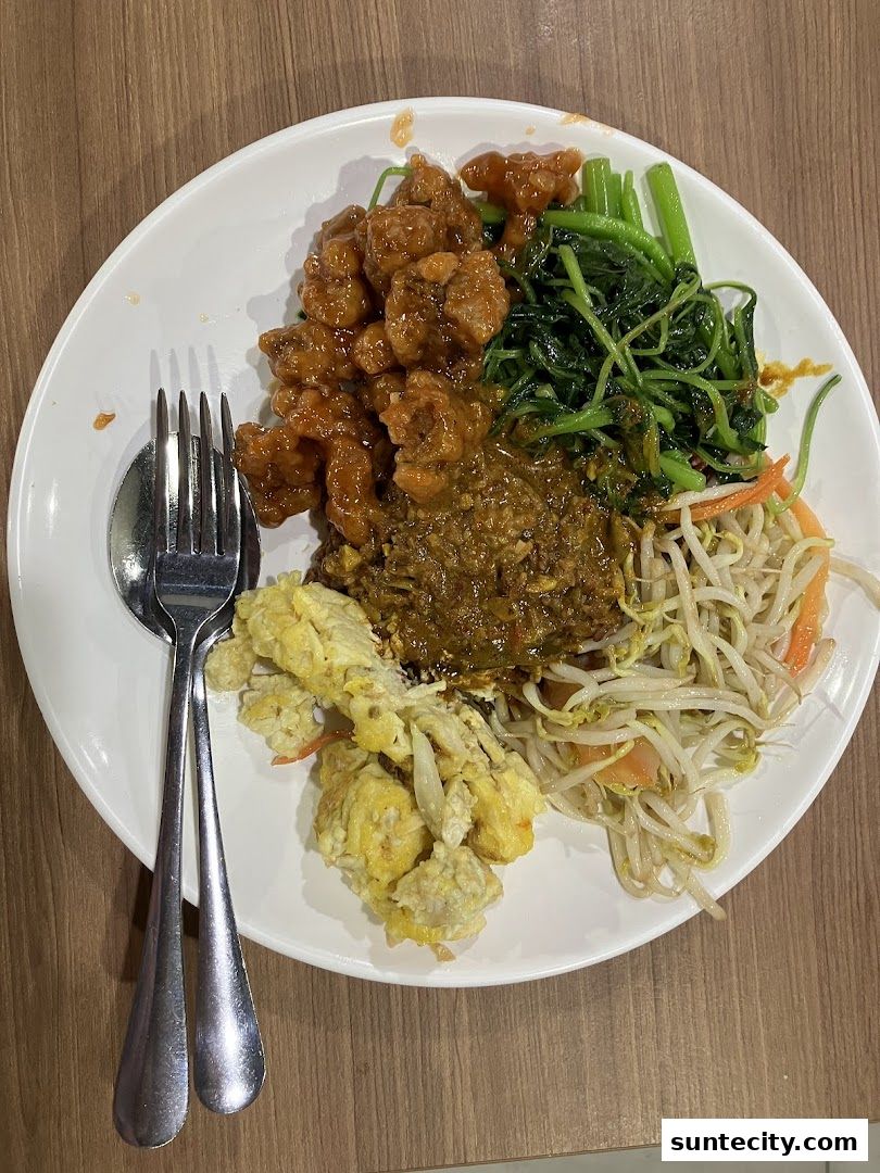 A plate of Teochew porridge with various side dishes including fried chicken, vegetables, and scrambled eggs.