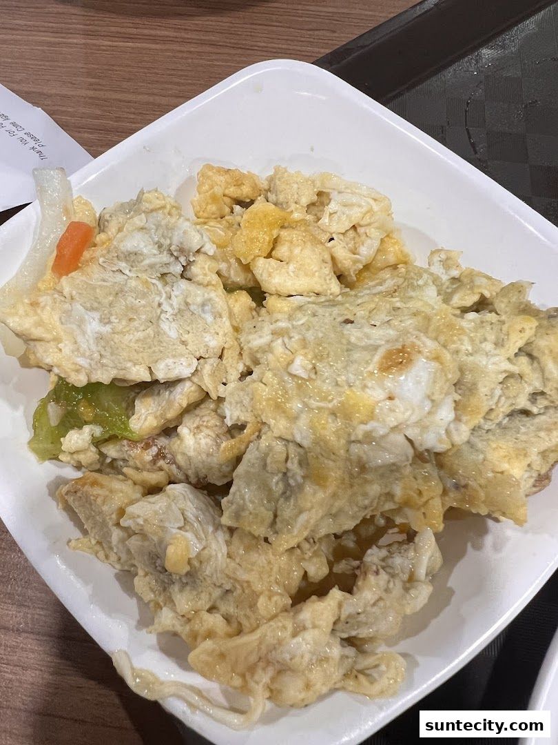 A close-up of a white bowl filled with scrambled eggs and vegetables.