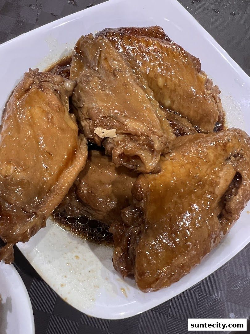 A plate of glistening braised chicken wings in a savory sauce.