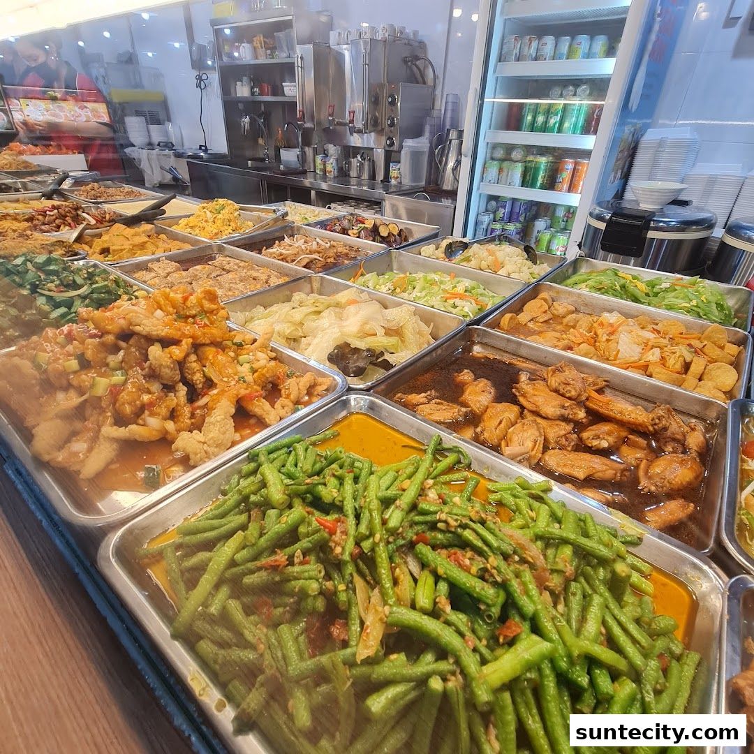 A wide selection of Teochew porridge dishes displayed in metal trays, ready to be served.