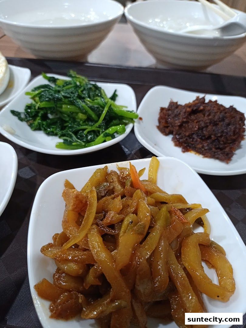 A close-up of several small dishes of Teochew porridge toppings and bowls.